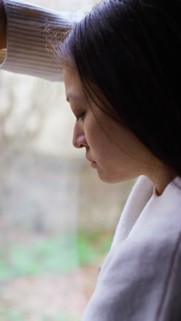 Vertical-Video-Close-Up-Of-Stressed-Or-Anxious-Woman-Suffering-With-Depression-Anxiety-Loneliness-Or-Agoraphobia-Leaning-Against-Window-At-Home-2